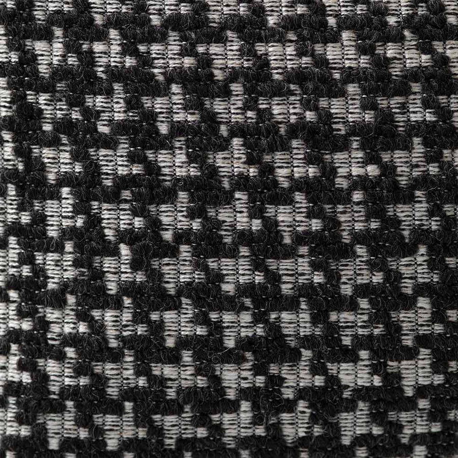 The Noirstone Lumbar Black-and-White Cushion by Urban Road (50x30cm) features a houndstooth pattern, ideal for enhancing interiors. Inspired by Darren Palmer and displayed on a crisp white background.