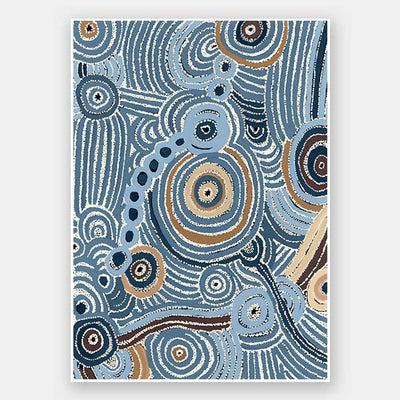 Concentric circle motifs and flowing white dot patterns in navy blue, sky blue, and ochre against a textured pale blue background. From the Maria Watson-Trudgett collection with Urban Road.