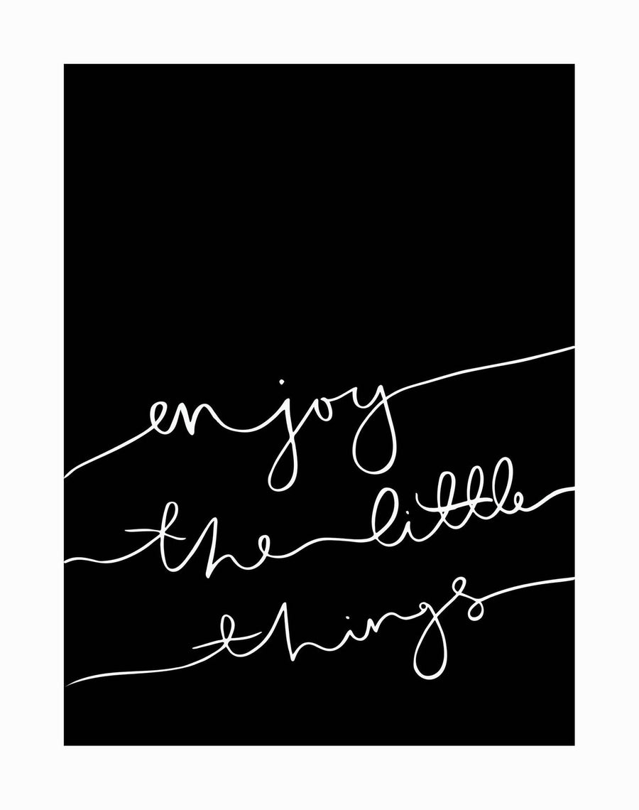 The Urban Road "Enjoy the little things" Unframed Art Print features white cursive text on black, with each word on its own line and joined by a continuous line in striking monochrome style.