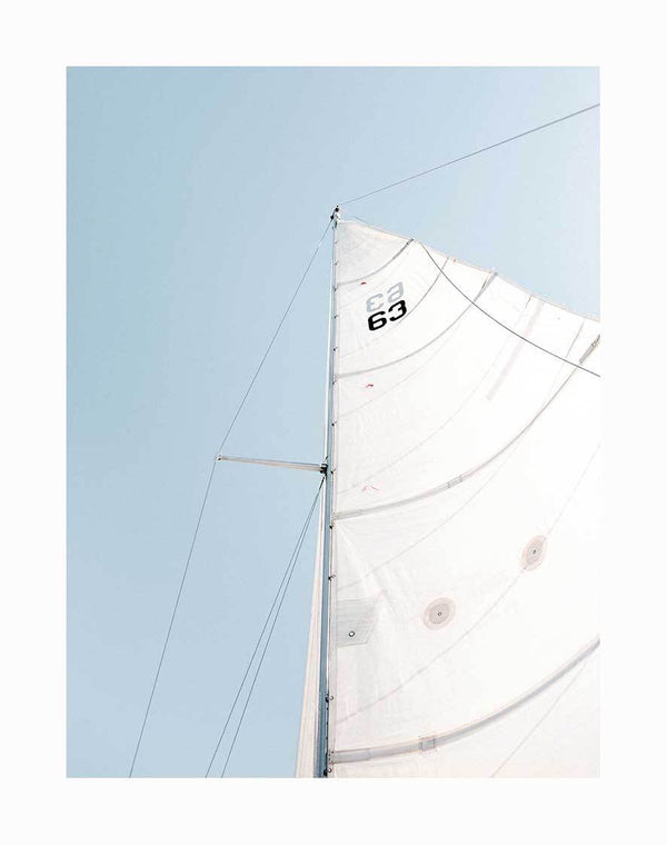 The Set Sail Unframed Art Print by Urban Road features a close-up view looking up at a sailboat's white sail and mast against a clear blue sky, with the number 63 in black near the top of the sail.