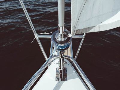The Urban Road Half Mast Unframed Art Print features a photographic view from a boat's bow with metal railings, rigging, a white sail, and dark blue waters in the background.