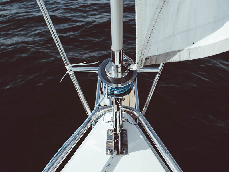 The Urban Road Half Mast Unframed Art Print features a photographic view from a boat's bow with metal railings, rigging, a white sail, and dark blue waters in the background.