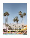 The Poolside at the Saguaro Unframed Art Print by Urban Road captures tall palms, yellow umbrellas, pink lounge chairs, and people relaxing by a vibrant pool at the Saguaro Hotel, set against mountains and a clear blue sky.