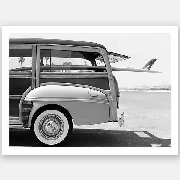 Barbara Ann Unframed Art Print by Urban Road: A black and white retro beach wagon with wood paneling and a surfboard, parked by swaying palms for timeless charm.