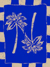 Vibrant coastal-inspired artwork featuring two cream palm trees with sweeping fronds on a bold cobalt blue background with a striped border, from the Shatha collection with Urban Road.