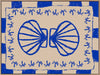 Symmetrical blue shell motif with palm-like flourishes, framed by a blue and cream checkered border on a neutral base, from the Shatha collection with Urban Road.