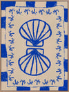 Symmetrical blue shell motif with palm-like flourishes, framed by a blue and cream checkered border on a neutral base, from the Shatha collection with Urban Road.