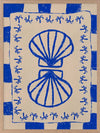 Symmetrical blue shell motif with palm-like flourishes, framed by a blue and cream checkered border on a neutral base, from the Shatha collection with Urban Road.