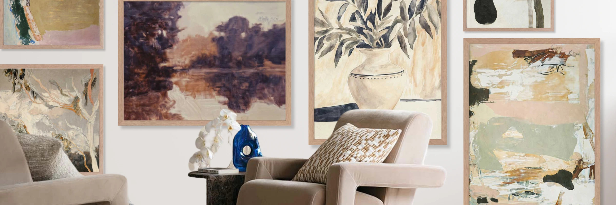 Gallery-style wall with framed abstract and nature-inspired art above a beige chair and marble side table with decor.