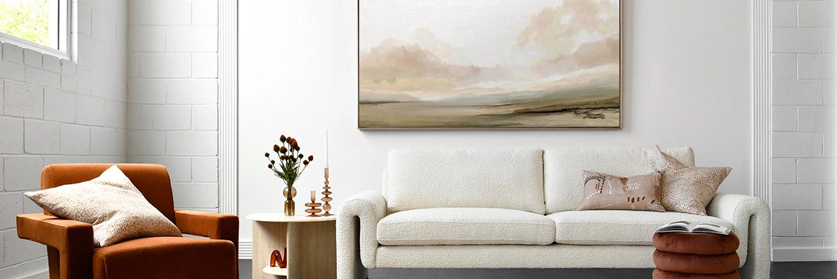 Calm, inviting lounge room featuring serene landscape art with soft, muted tones above a cosy white sofa.